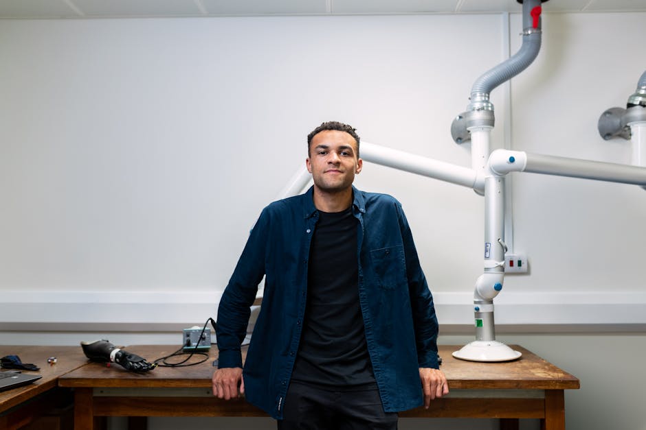 Confident young engineer standing in a laboratory with advanced robotic equipment